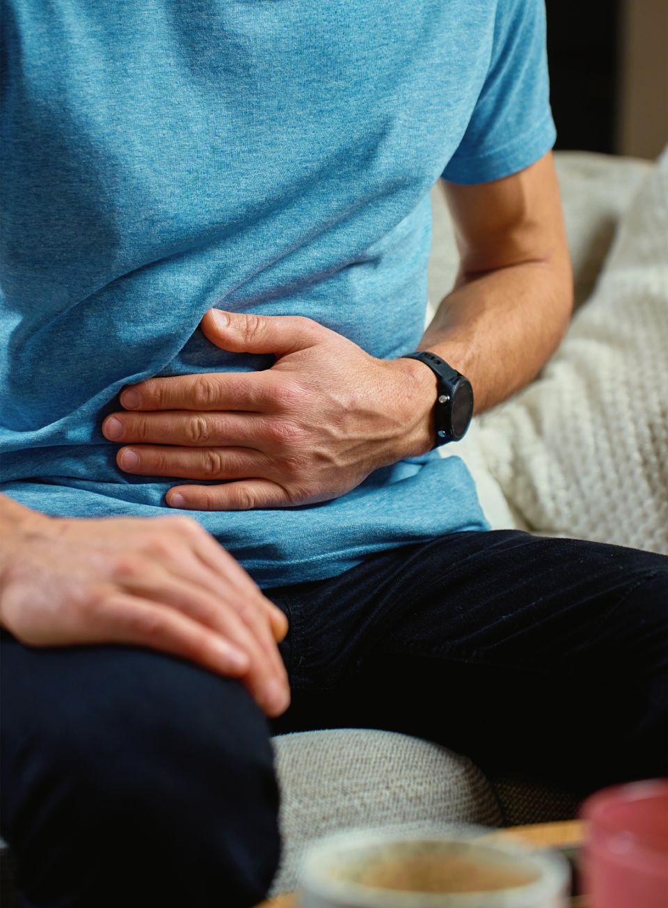 Person resting hand on abdomen while seated, representing digestive comfort