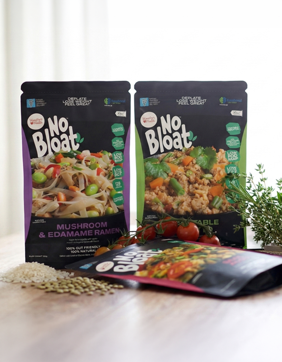 No Bloat meal pouches with fresh ingredients on a wooden surface