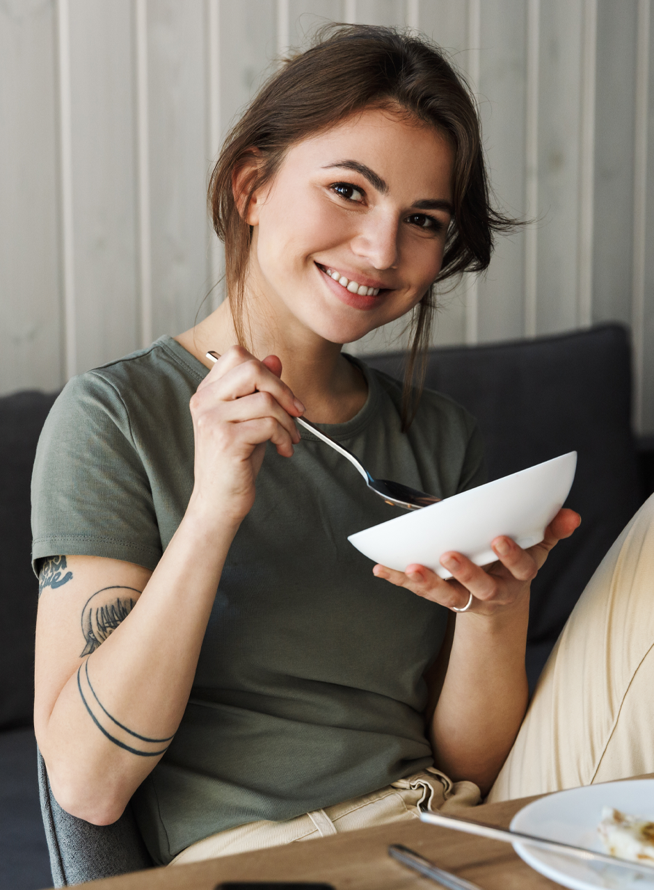 Woman smiling while eating from a bowl, representing the FODMAP maintenance lifestyle